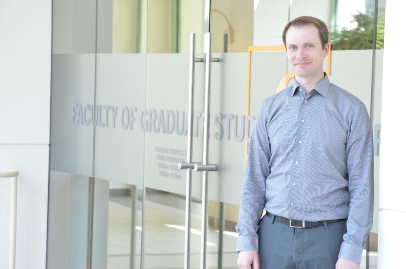 Benjamin Freitag stands in front of the Faculty of Graduate Studies Office