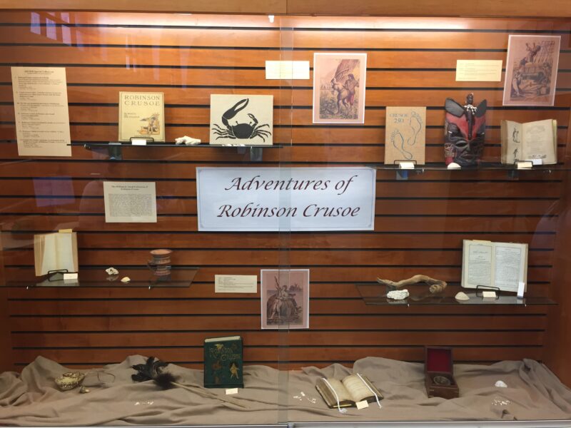 A display of various books and items related to the novel "Adventures of Robinson Crusoe".