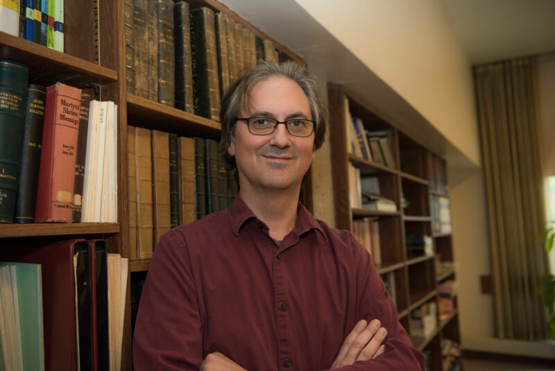 Headshot of Dwayne Meisner standing in front of a bookshelf.